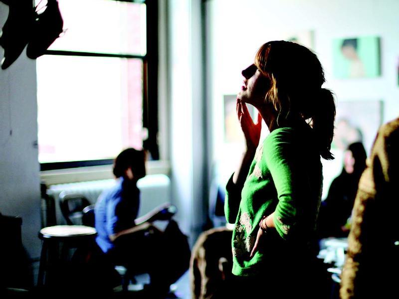 Young woman standing in a classroom, looking thoughtful